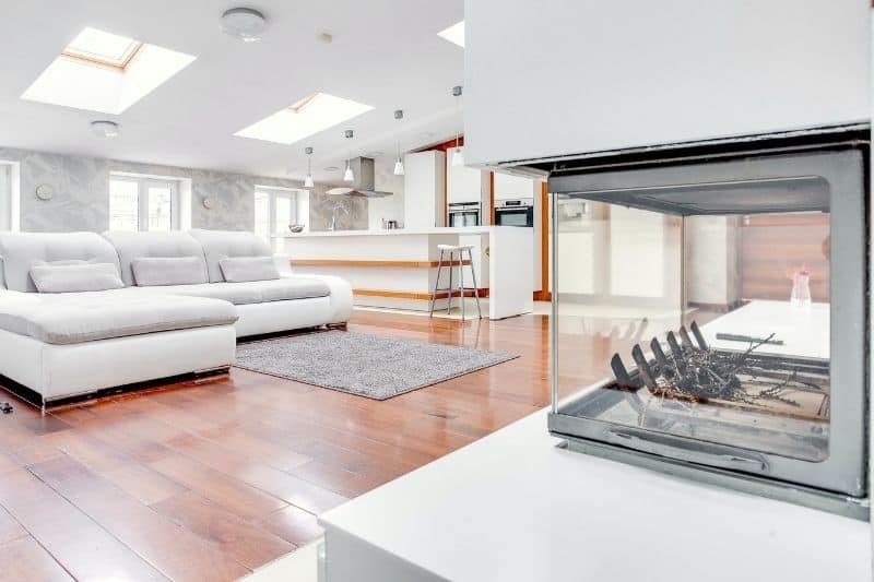 Großes, lichtdurchflutetes Penthouse-Wohnzimmer mit kaltem Kamin und leerer Atmosphäre
